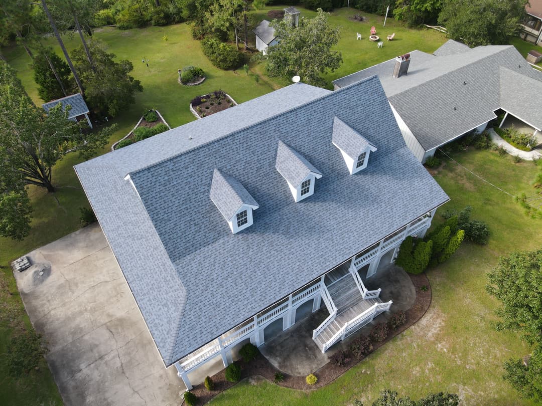 Aerial view of a house with a gray roof and landscaped yard, showcasing outdoor features.