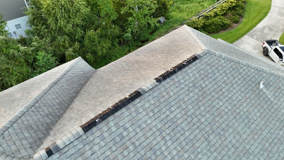 Damaged roof shingles on a house, showing wear and potential leakage issues.