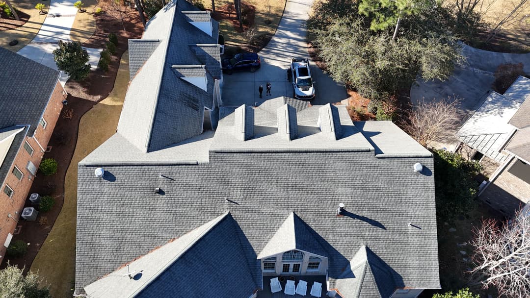 Aerial view of residential roofs and a driveway with parked cars.