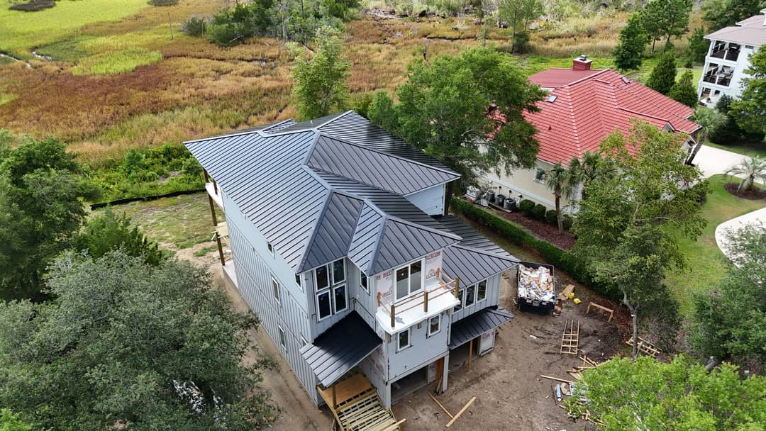 Aerial view of a modern two-story house under construction surrounded by greenery.