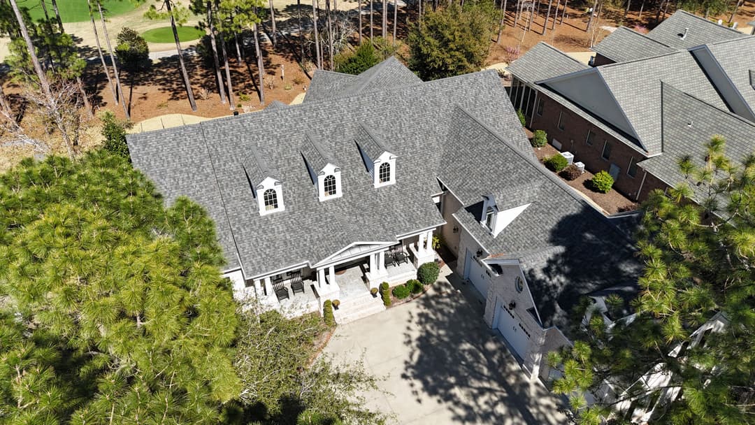 Aerial view of a stylish suburban home with a gray roof and manicured landscaping.