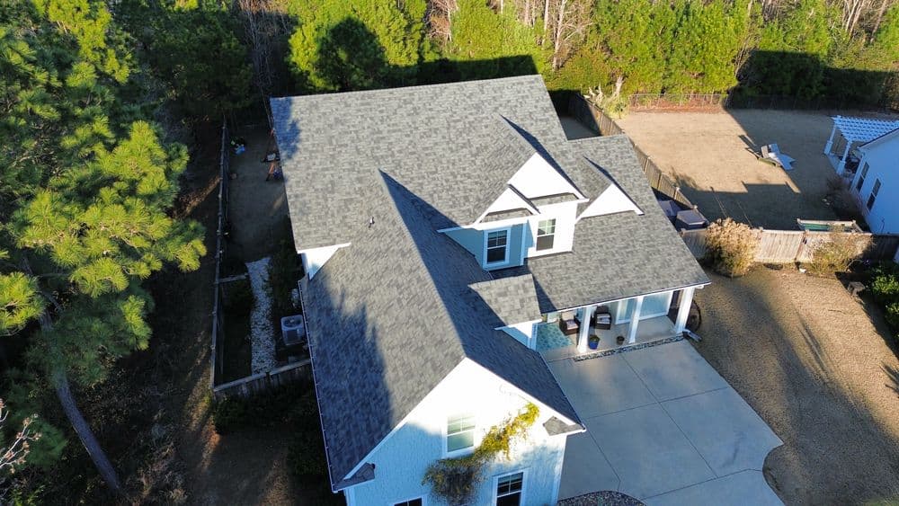 Aerial view of a modern two-story house with a gray roof and surrounding greenery.